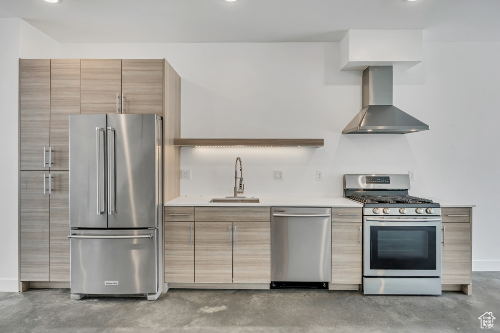 Kitchen featuring appliances with stainless steel finishes, wall chimney exhaust hood, modern cabinets, concrete flooring, and light countertops