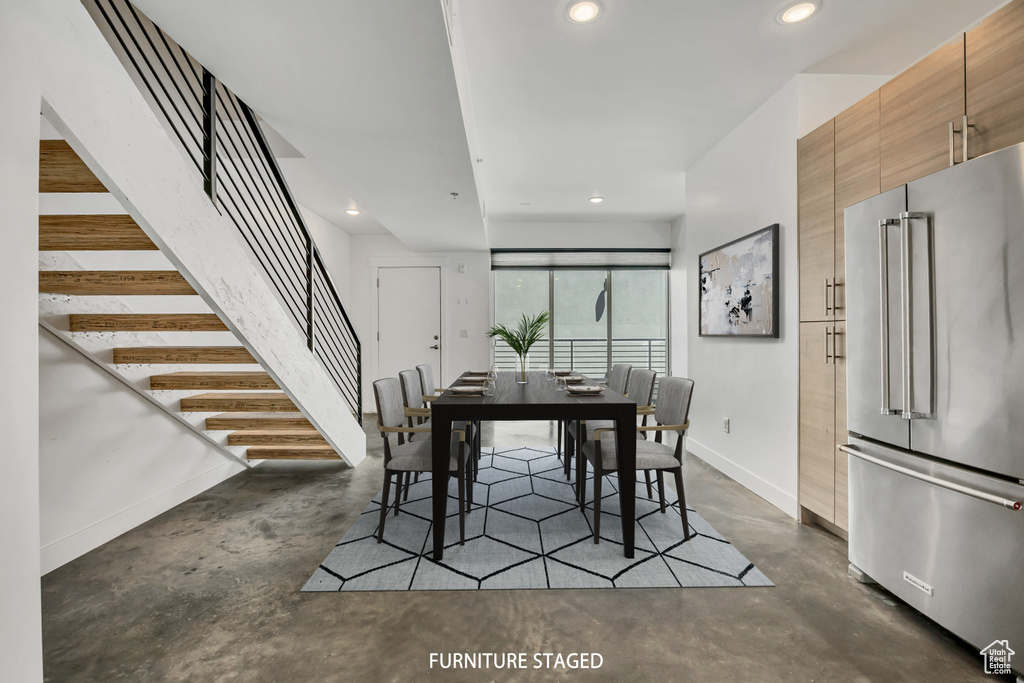 Dining area featuring concrete flooring, stairs, and recessed lighting