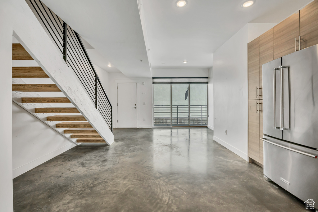Unfurnished living room featuring concrete flooring, recessed lighting, and stairs