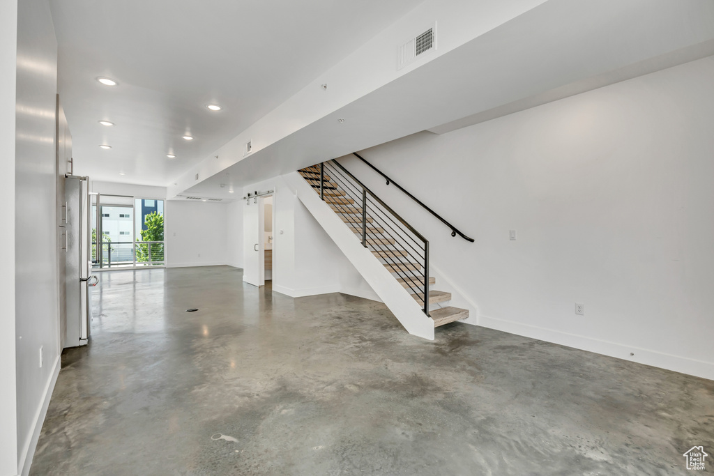 Basement with stairs, recessed lighting, and freestanding refrigerator
