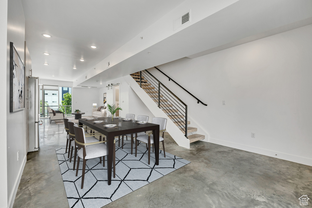 Dining space with finished concrete flooring, stairs, and recessed lighting