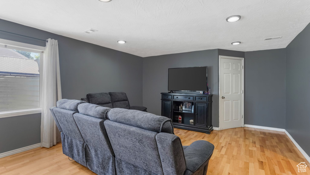 Living room with light wood-style flooring and recessed lighting