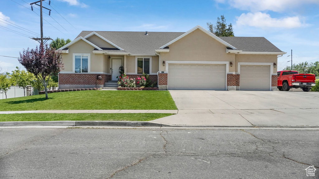 View of front of home featuring a garage, stucco siding, a front yard, and driveway