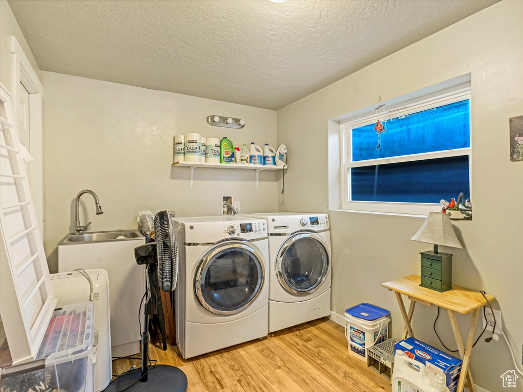 Laundry area featuring washing machine and clothes dryer, wood finished floors, and a textured ceiling