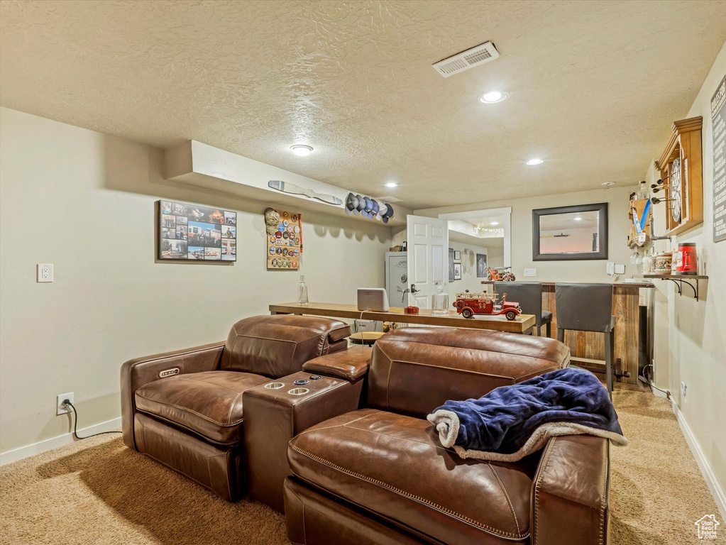 Home theater featuring light colored carpet, a dry bar, a textured ceiling, and recessed lighting