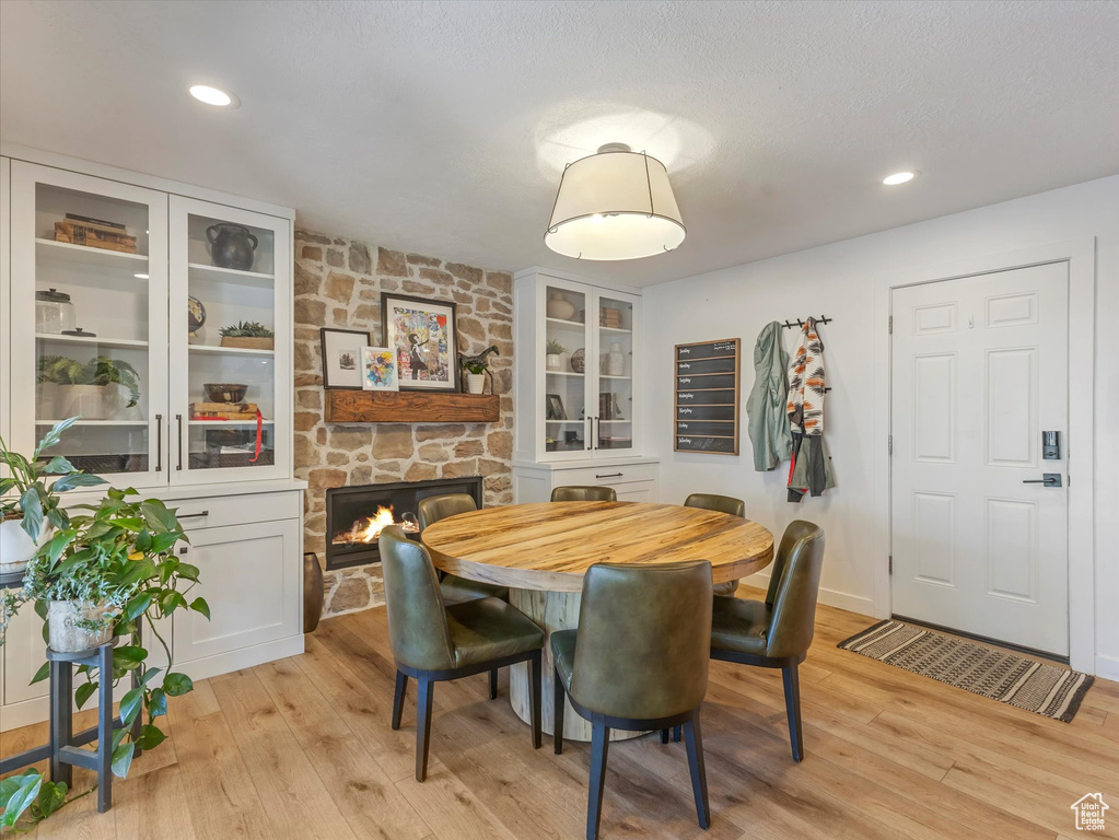 Dining area featuring a stone fireplace, light wood-style flooring, and recessed lighting