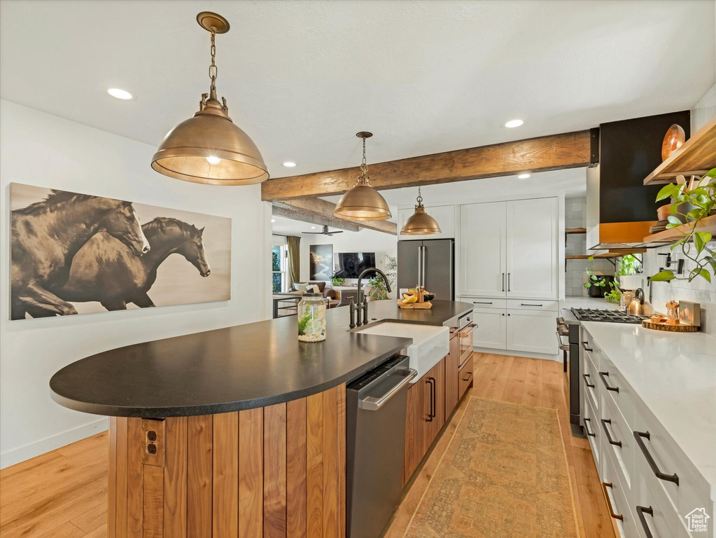 Kitchen with premium appliances, light wood-style flooring, a center island with sink, white cabinetry, and recessed lighting