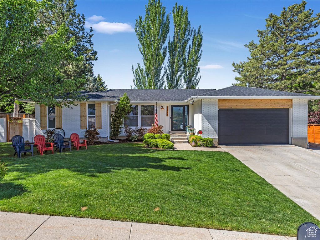 Single story home with an attached garage, driveway, and brick siding