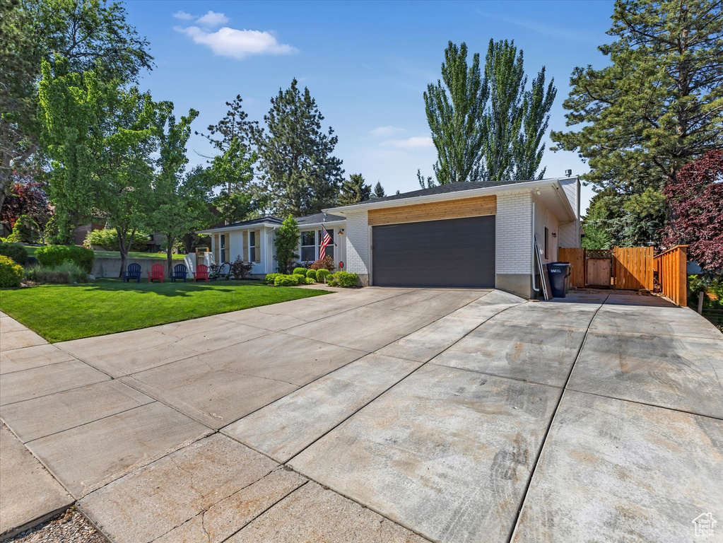 View of front facade with an attached garage, concrete driveway, brick siding, and a gate
