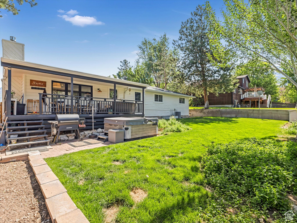 Back of house featuring a hot tub and a chimney
