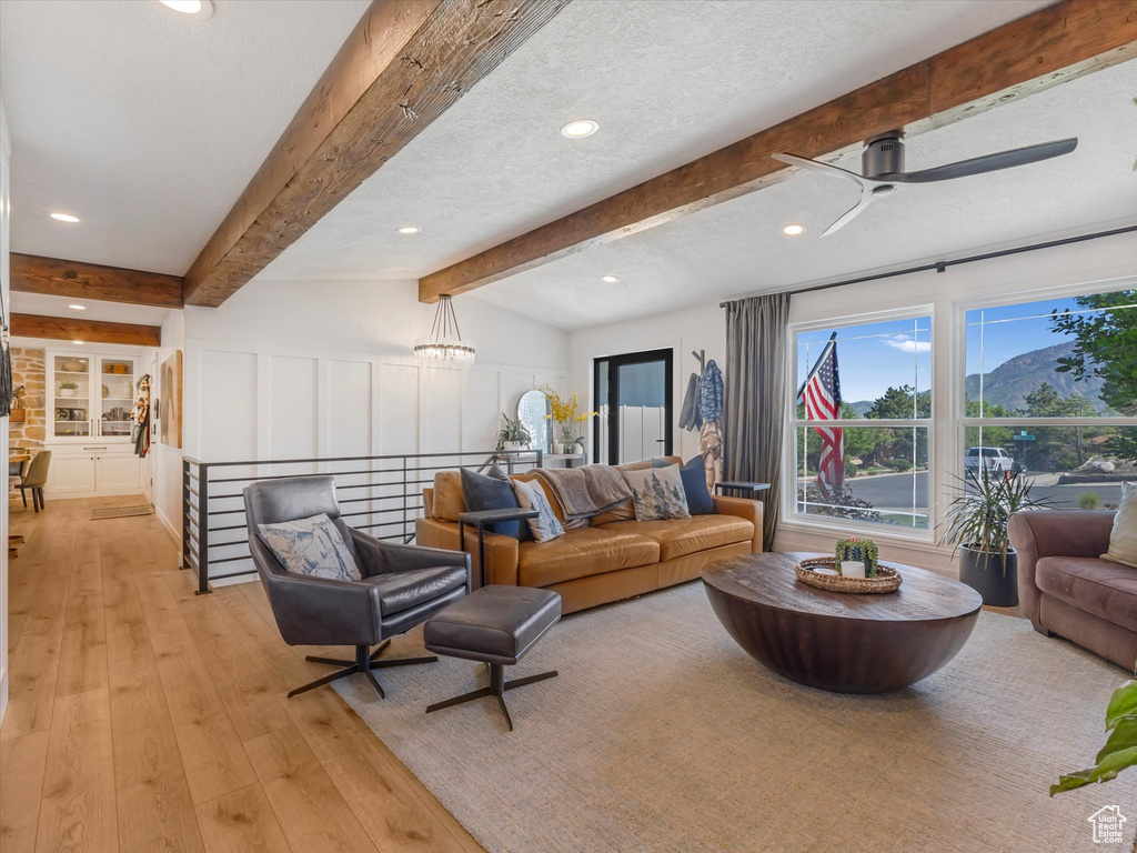 Living area featuring light wood finished floors, beam ceiling, recessed lighting, and ceiling fan