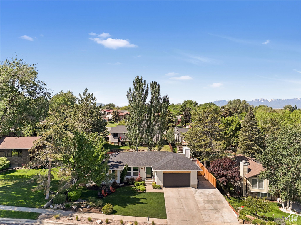 View of front facade featuring a garage, driveway, a front yard, and a residential view