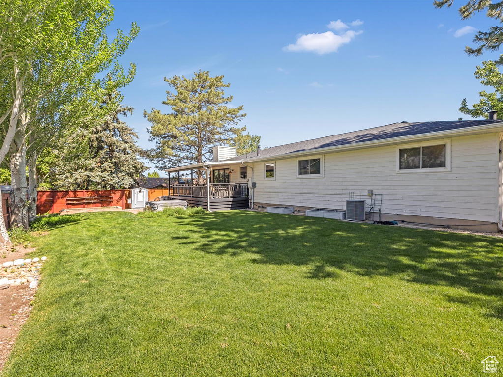 Rear view of house with a deck, a fenced backyard, a storage unit, and a chimney