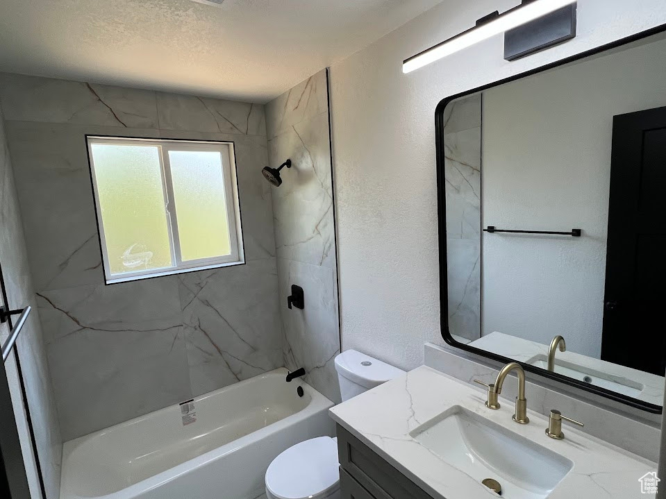Full bath with vanity,  shower combination, and a textured wall