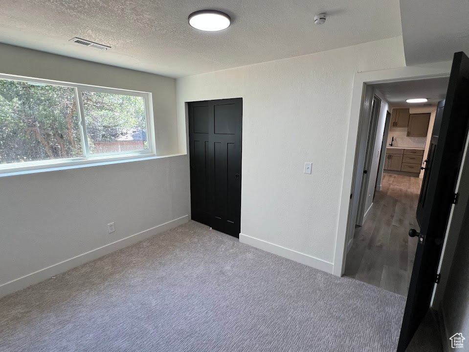 Unfurnished bedroom featuring a textured ceiling, carpet, and a closet