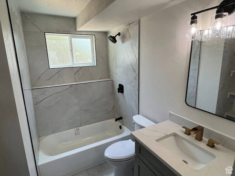 Bathroom featuring vanity, shower / washtub combination, marble finish floors, and a textured wall