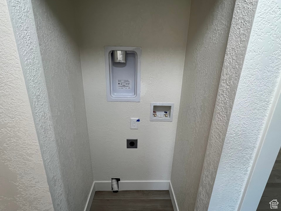 Laundry area featuring electric dryer hookup, wood finished floors, washer hookup, and a textured wall