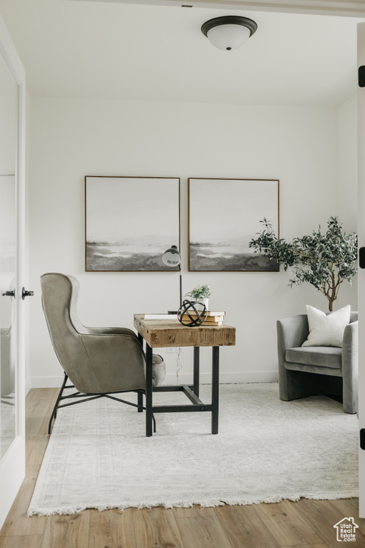 Sitting room with wood finished floors and a desk