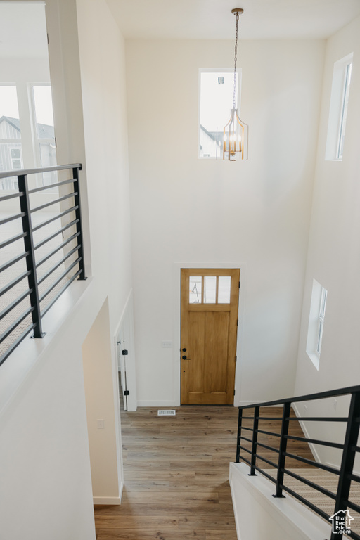Foyer with a towering ceiling, wood finished floors, a chandelier, and plenty of natural light