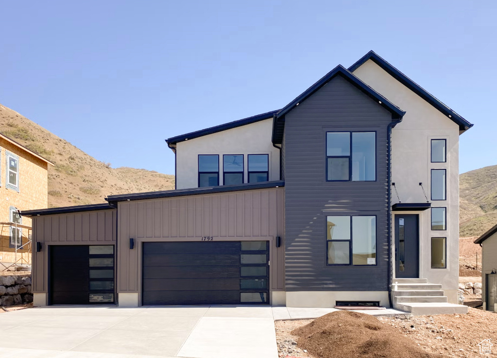 Modern home with concrete driveway, a garage, and a mountain view