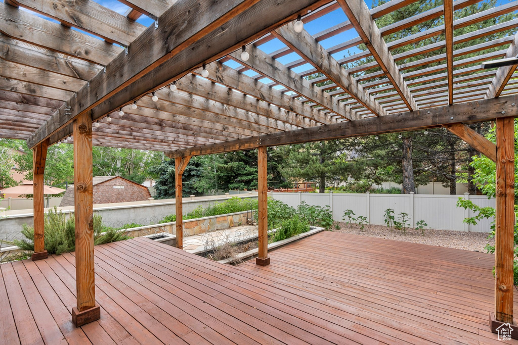 Wooden terrace with a fenced backyard and a pergola