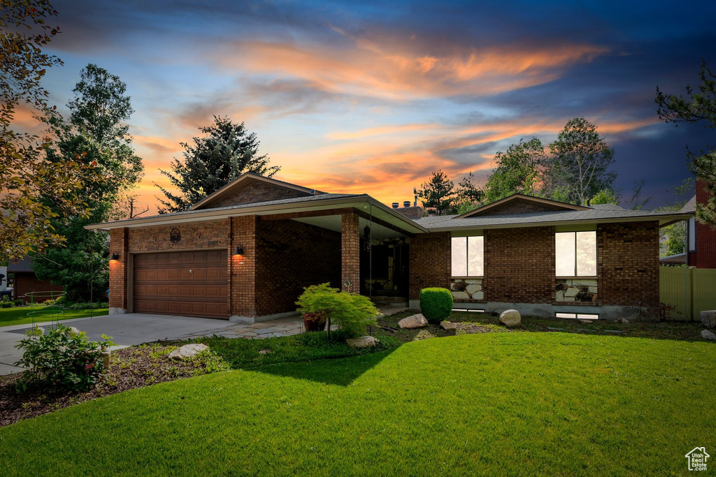 View of front facade with a garage, driveway, brick siding, and a front lawn