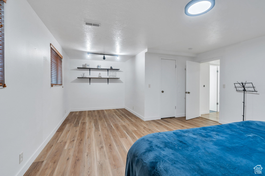 Bedroom with light wood-style floors and a textured ceiling