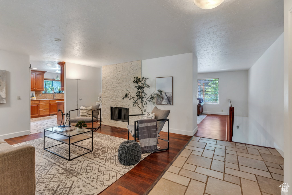 Living room with a fireplace, light wood finished floors, and a textured ceiling