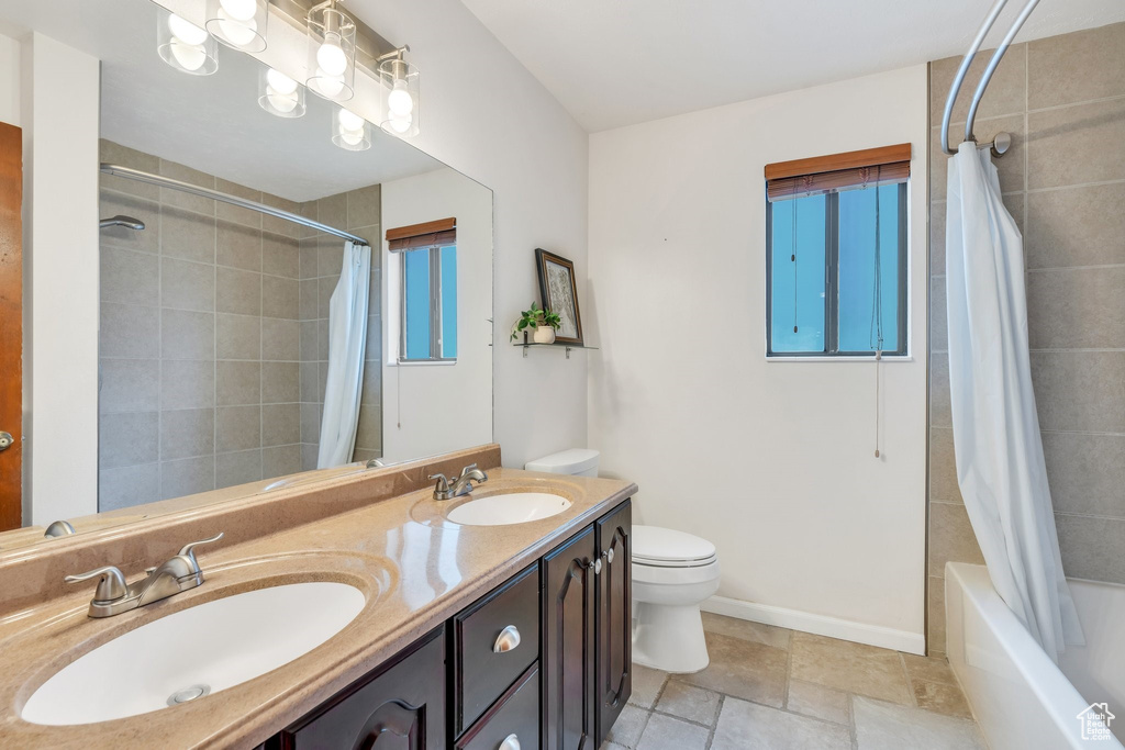 Bathroom featuring shower / bath combination with curtain and double vanity