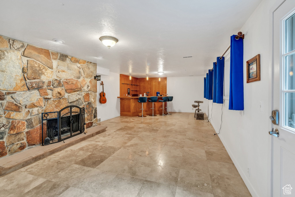Living room featuring bar with sink and a stone fireplace