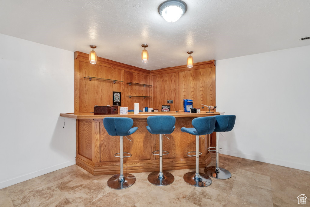Indoor dry bar with baseboards and hanging light fixtures