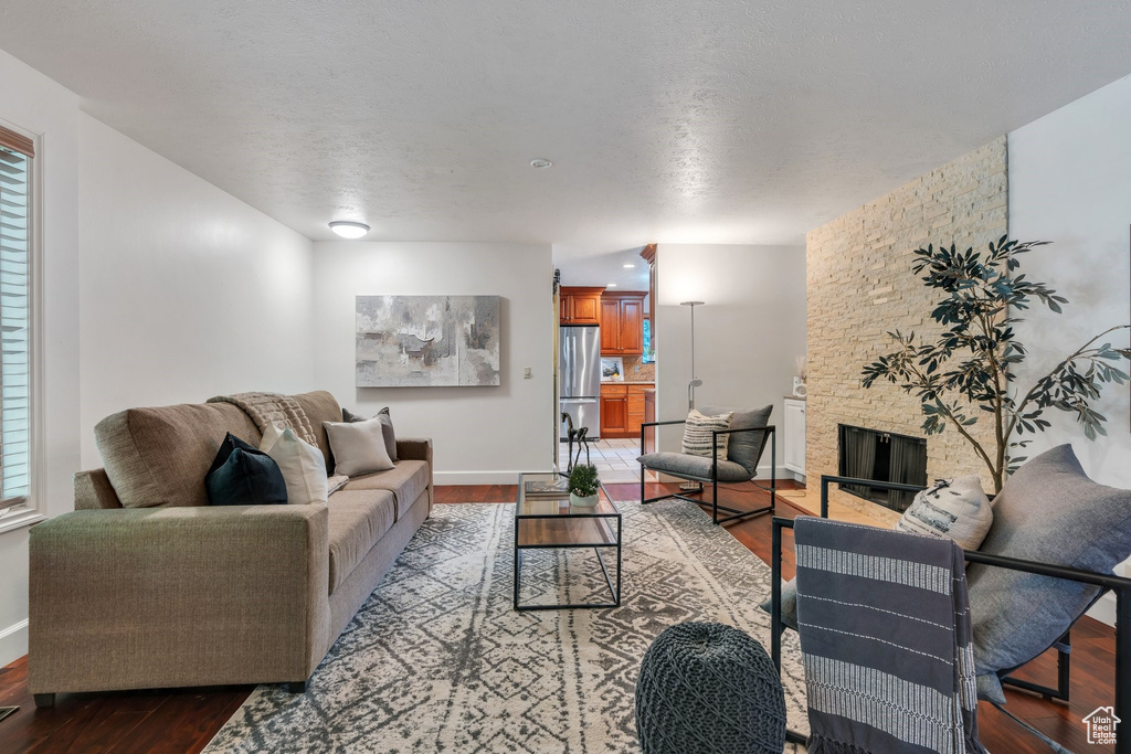 Living area with wood finished floors, a stone fireplace, and healthy amount of natural light