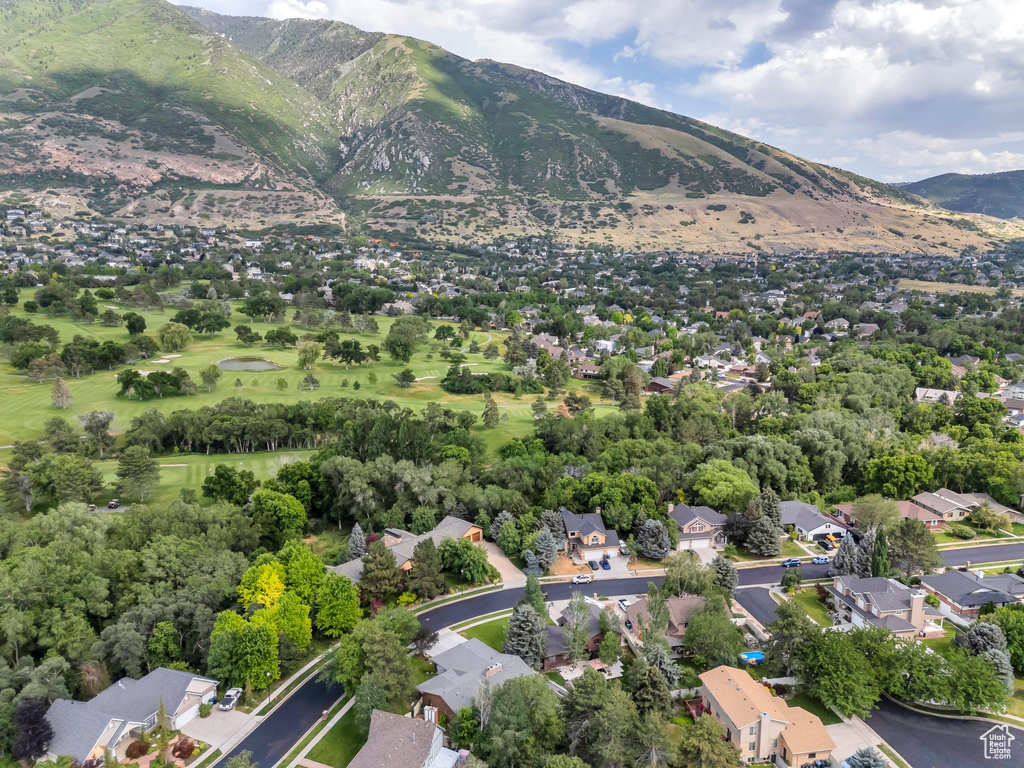 Aerial view of property and surrounding area featuring a mountainous background and nearby suburban area