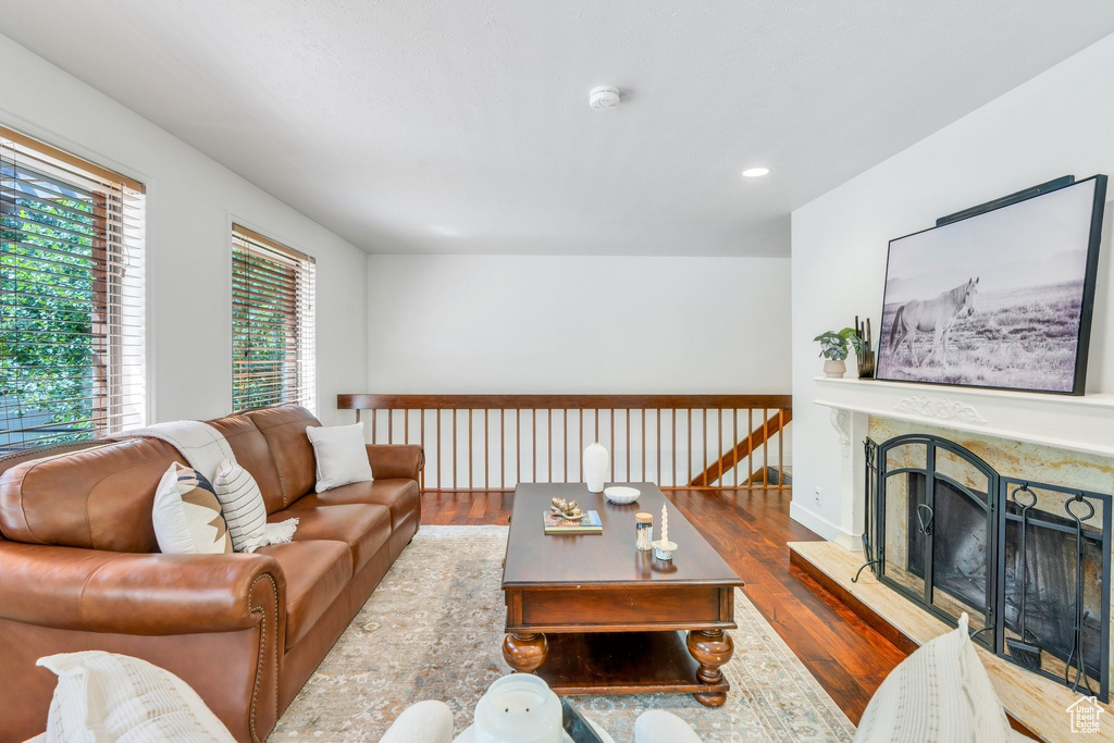 Living area with wood finished floors, a fireplace with raised hearth, and recessed lighting