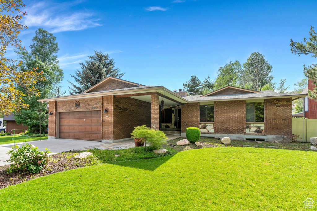 Single story home featuring an attached garage, driveway, brick siding, and a chimney