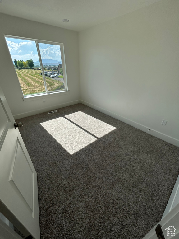 Carpeted spare room featuring baseboards