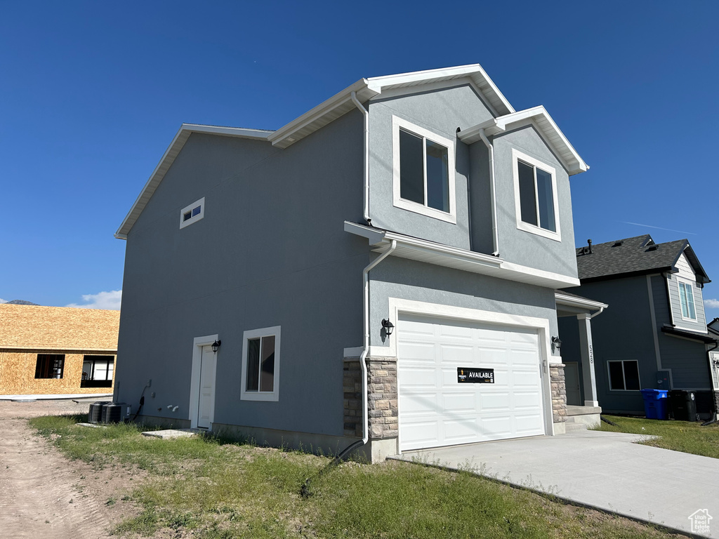 Traditional-style home with driveway, a garage, stucco siding, and stone siding