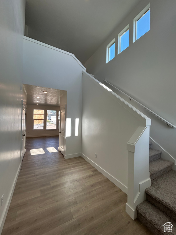 Unfurnished living room with plenty of natural light, a high ceiling, wood finished floors, and stairway