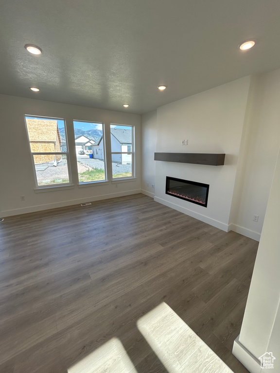 Unfurnished living room with a glass covered fireplace, recessed lighting, and wood finished floors