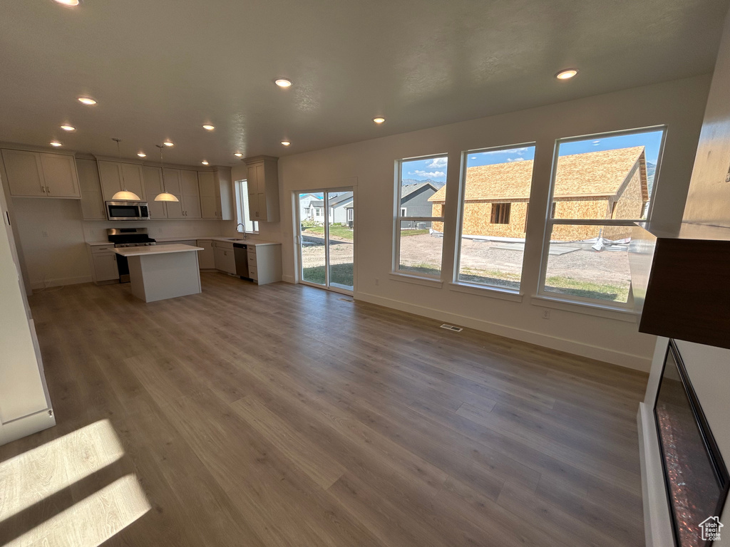 Kitchen featuring appliances with stainless steel finishes, a kitchen island, recessed lighting, wood finished floors, and light countertops