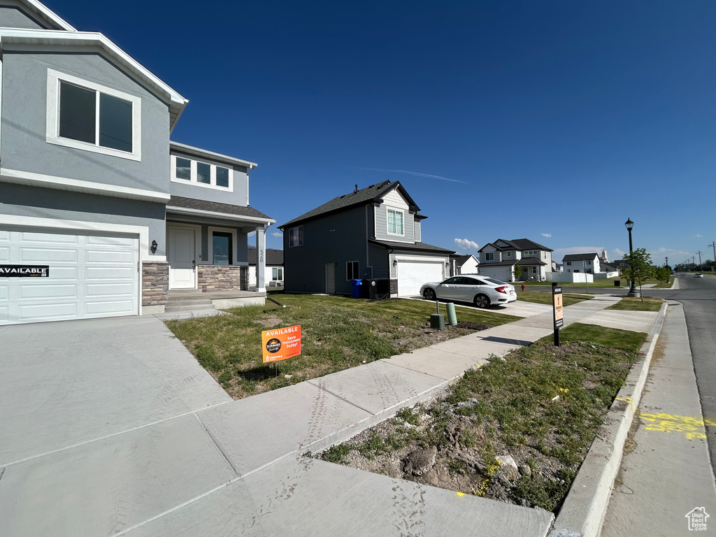 View of front of property featuring stone siding, stucco siding, a garage, a residential view, and a front yard