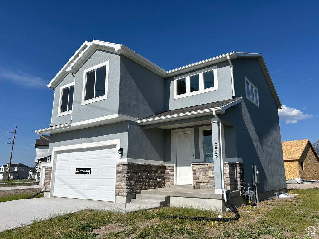 View of front of property with a garage, stone siding, stucco siding, and driveway