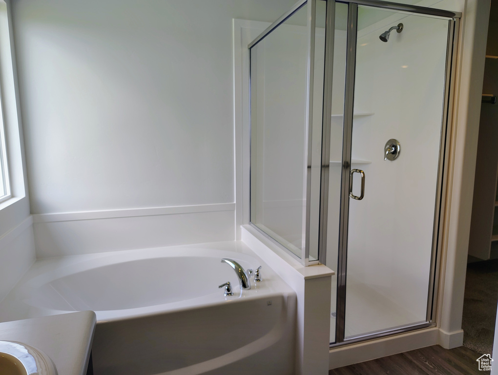 Bathroom featuring a stall shower, a garden tub, wood finished floors, and vanity