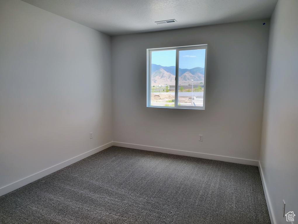 Unfurnished room featuring dark colored carpet