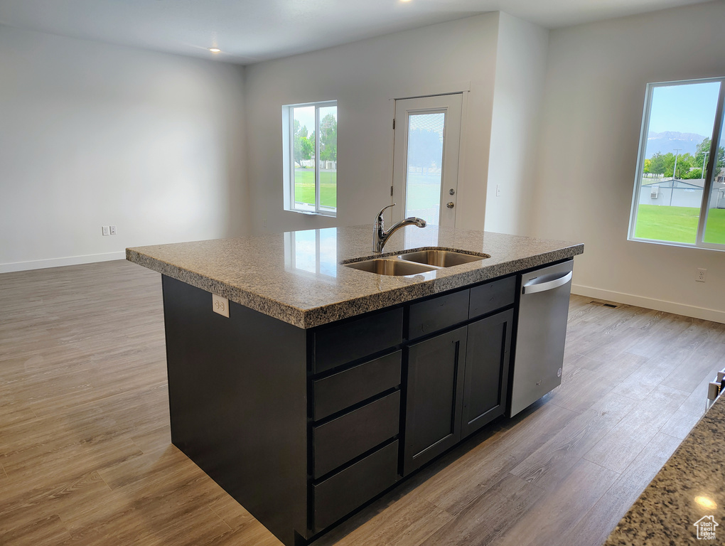 Kitchen featuring stainless steel dishwasher, plenty of natural light, a kitchen island with sink, and light wood-style flooring