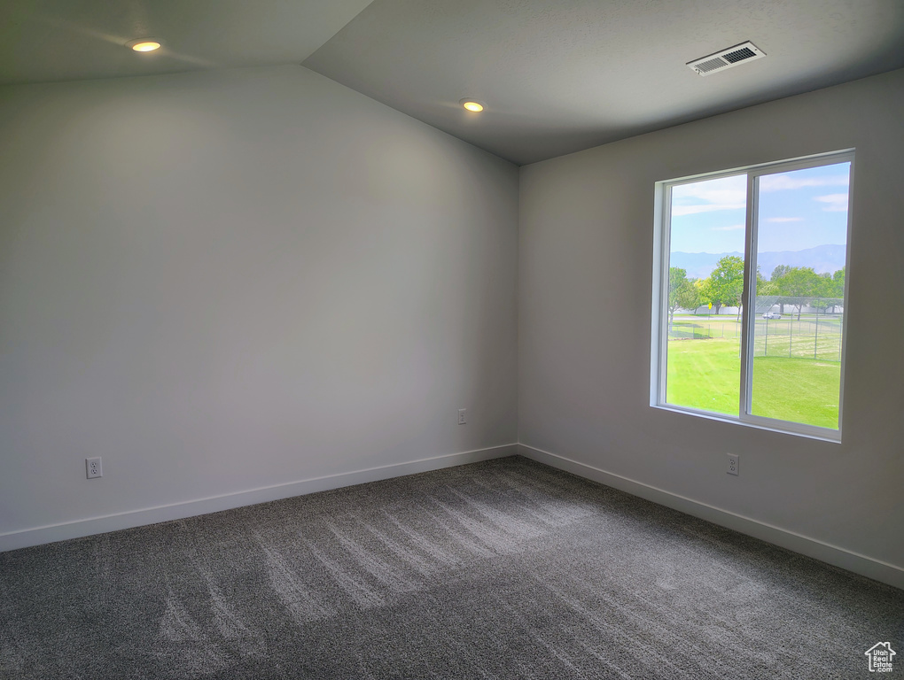 Unfurnished room featuring dark colored carpet, vaulted ceiling, and recessed lighting