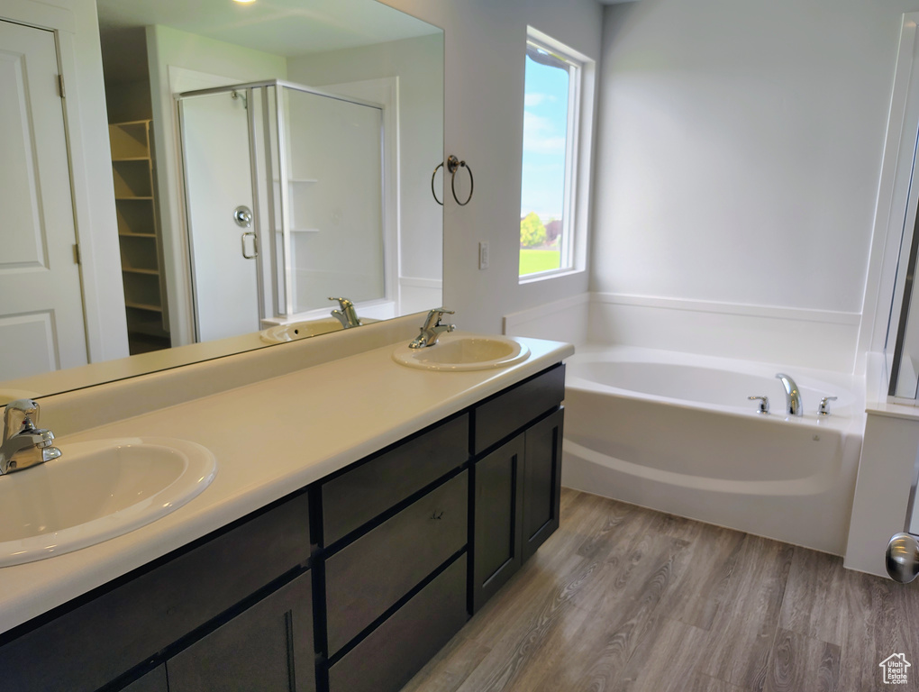 Bathroom featuring a shower stall, a garden tub, wood finished floors, and double vanity