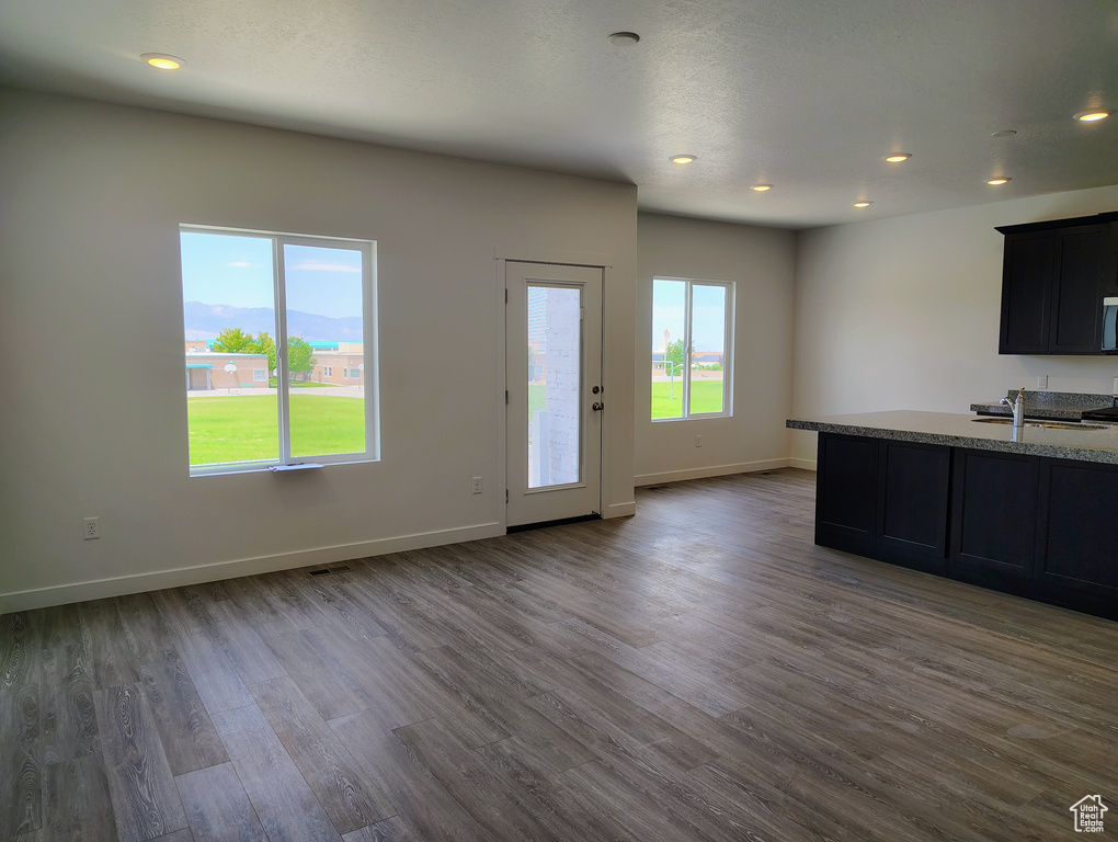 Kitchen with dark wood-type flooring, recessed lighting, open floor plan, and light stone counters