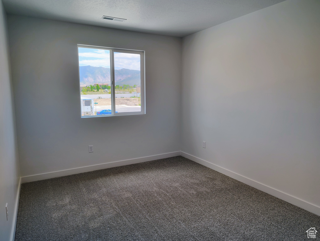 Spare room featuring dark colored carpet and a mountain view