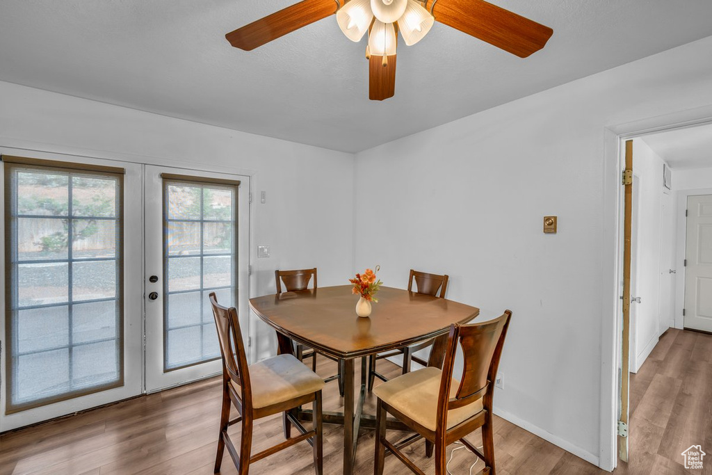 Dining room with french doors, wood finished floors, and a ceiling fan